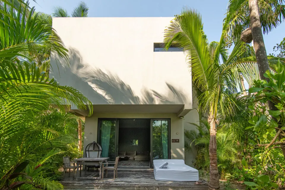 Exterior townhouse terrace with daybed and private tub surrounded by palms at Casa Malca