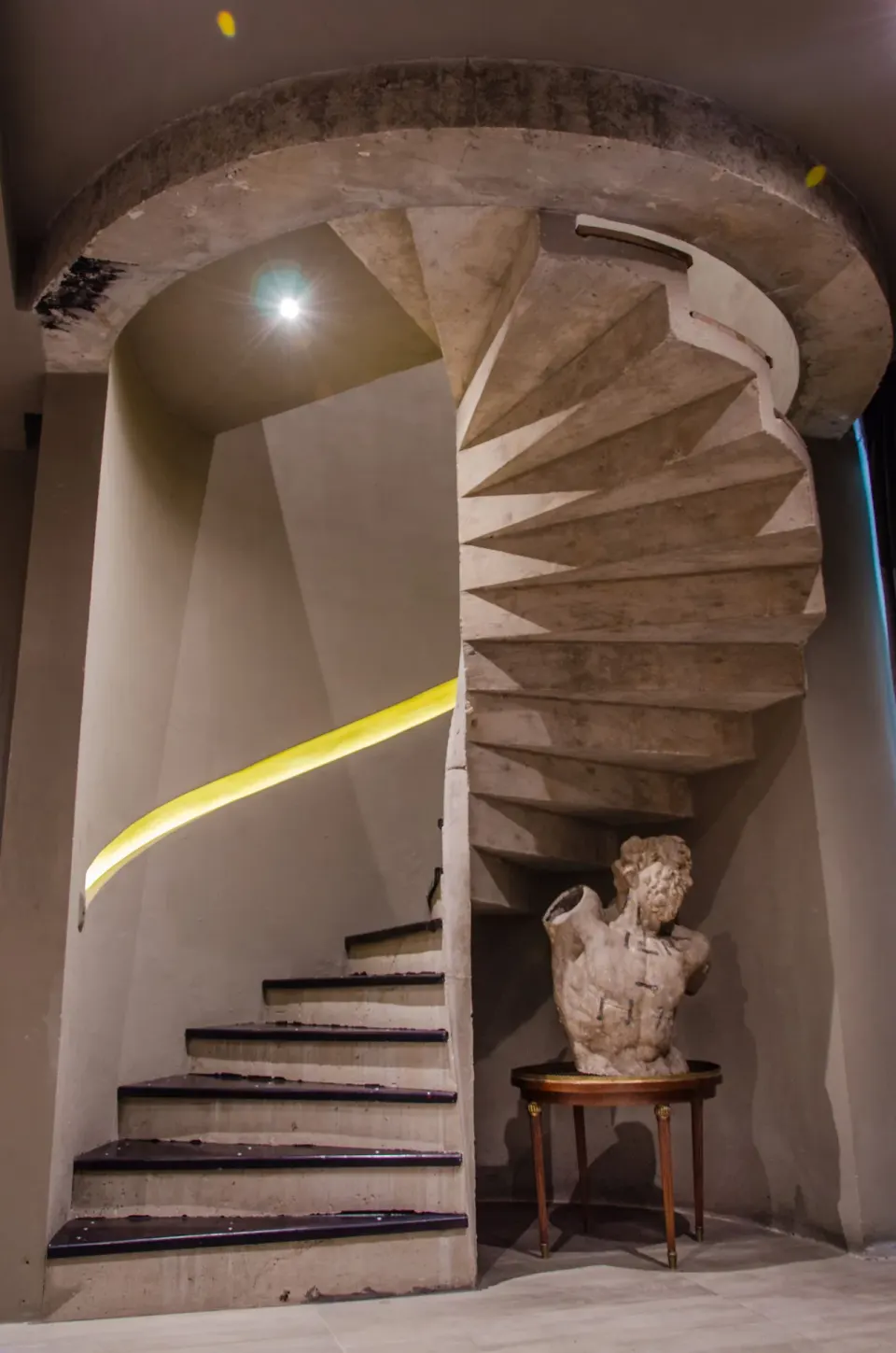 Spiral concrete staircase with sculptural bust at Casa Malca