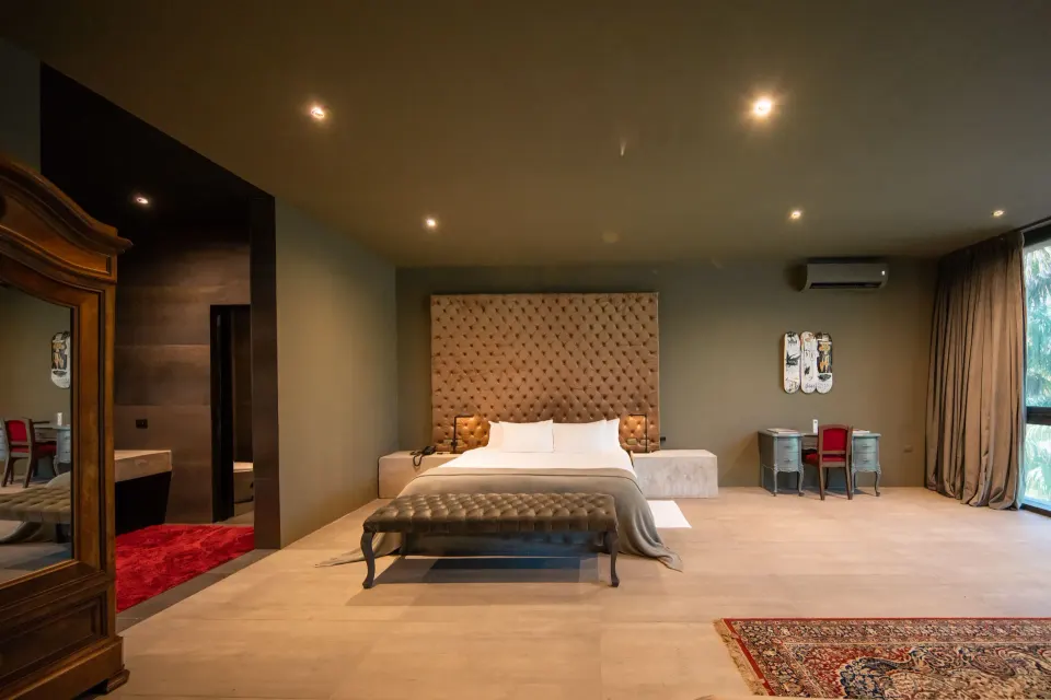 King bed centered in suite with decorative headboard and bedside tables at Casa Malca