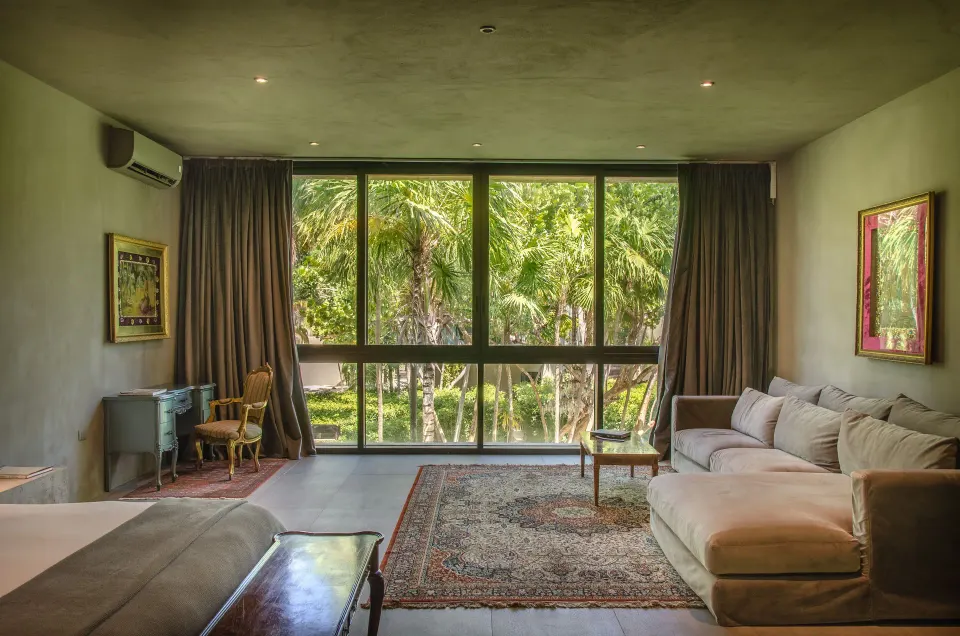Garden-facing suite window with chaise lounge and leafy view at Casa Malca