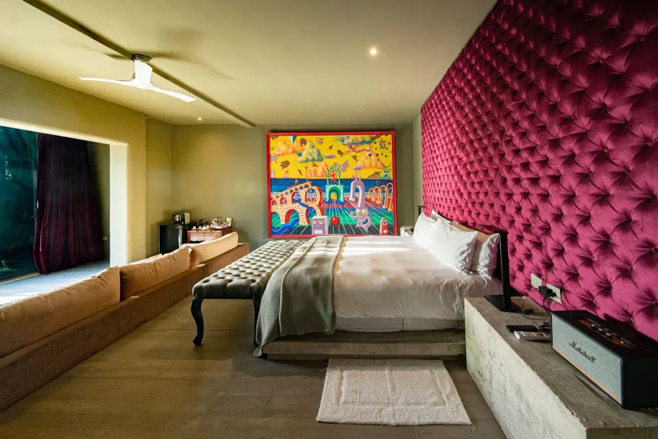 Suite with king bed, tufted pink headboard and colorful wall mural at Casa Malca
