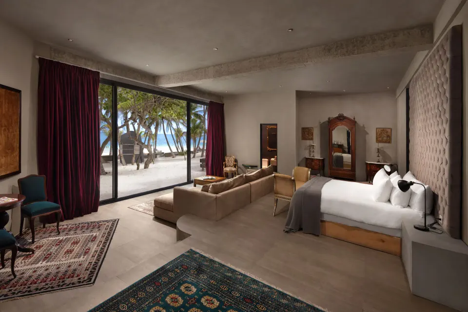Beachfront suite interior with king bed, sofa and sand-visible patio at Casa Malca