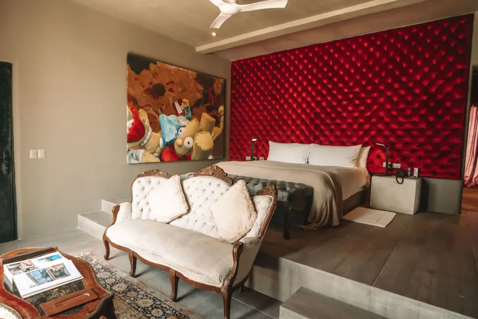 King bed in suite with tufted red headboard and vintage sofa at Casa Malca