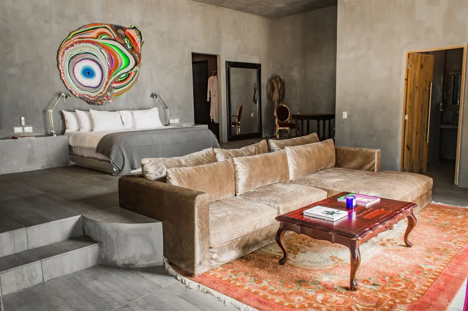 Spacious suite living area with a low king bed, velvet sofa and colorful wall art at Casa Malca.