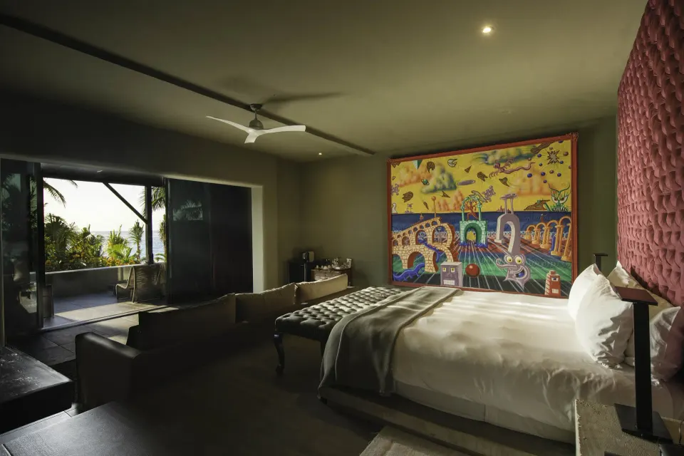 Dimly lit suite with king bed, tufted headboard and balcony view at Casa Malca