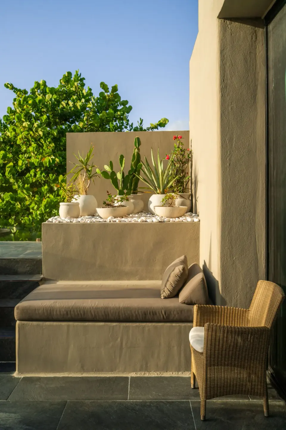Private terrace seating with built-in bench, plants and wicker chair at Casa Malca