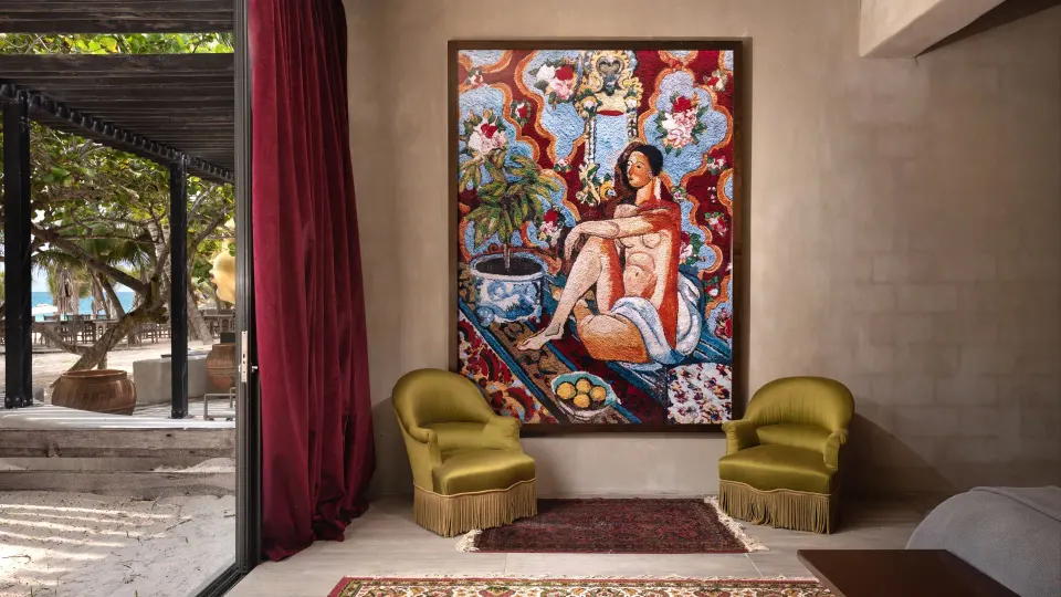 Seating nook with colorful painting and view through doors to beach at Casa Malca