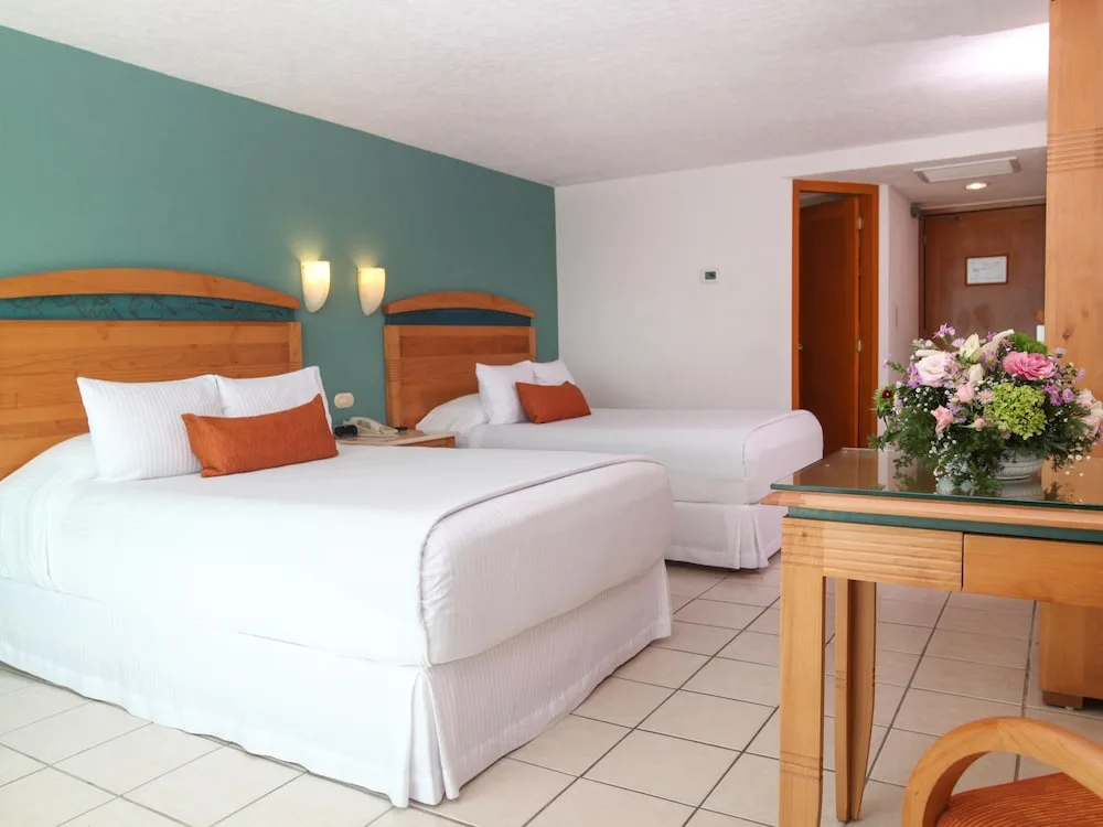 Bright guest room with two double beds and desk at Casa Mexicana Cozumel