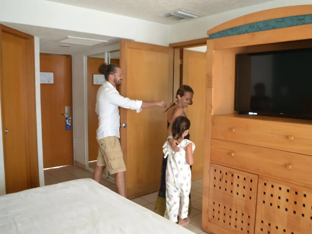 Family entering a guest room corridor and stepping into the room at Casa Mexicana Cozumel.