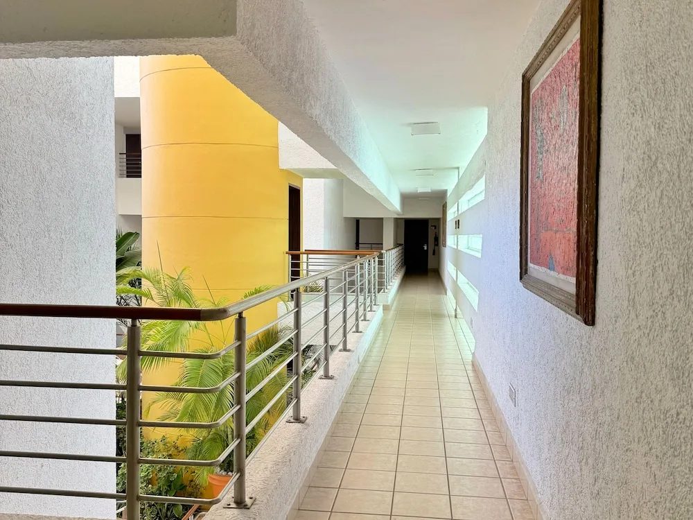 Open guest-floor hallway with railings and potted plants at Casa Mexicana Cozumel.