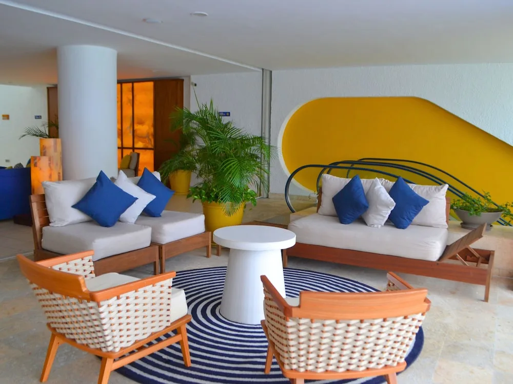 Lobby seating area at Casa Mexicana Cozumel with sofas, round table and a yellow decorative wall