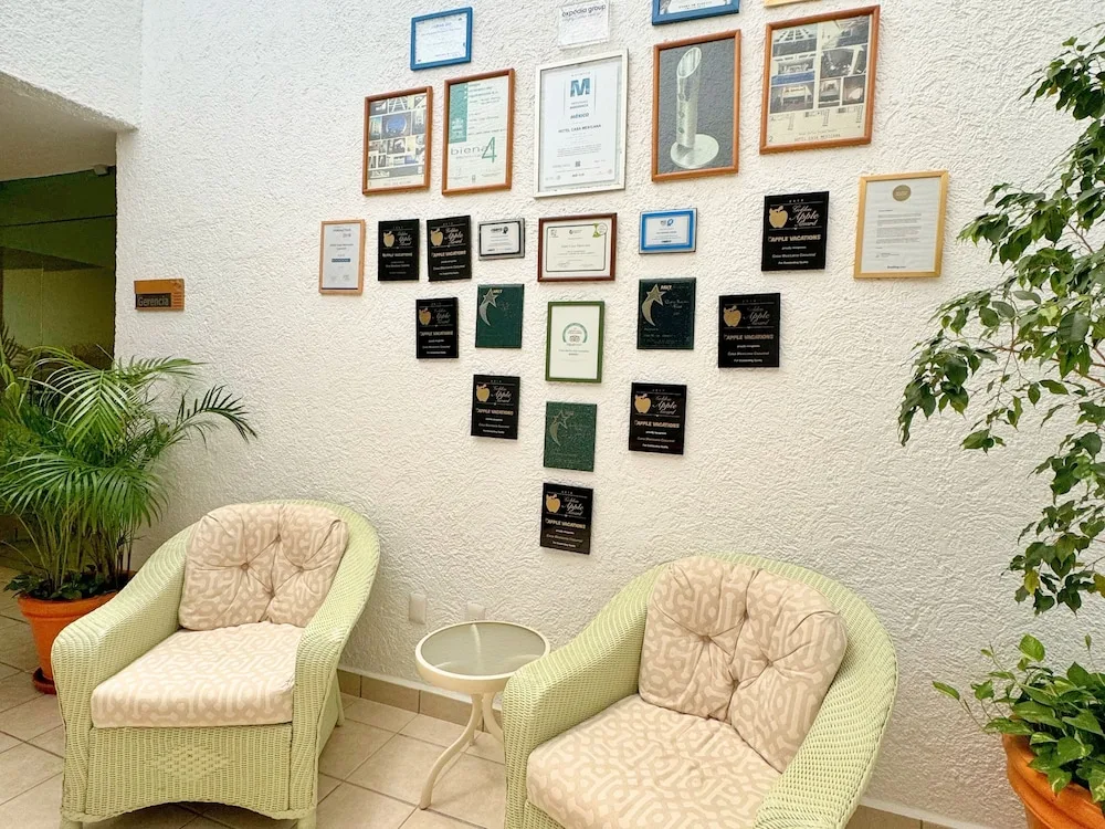 Seating nook with armchairs and wall of framed awards at Casa Mexicana Cozumel