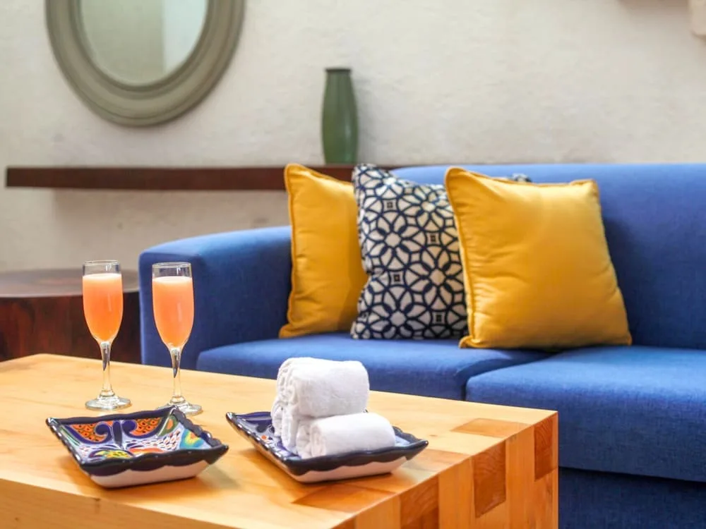Blue sofa with yellow cushions and drinks on a wooden table at Casa Mexicana Cozumel lobby.