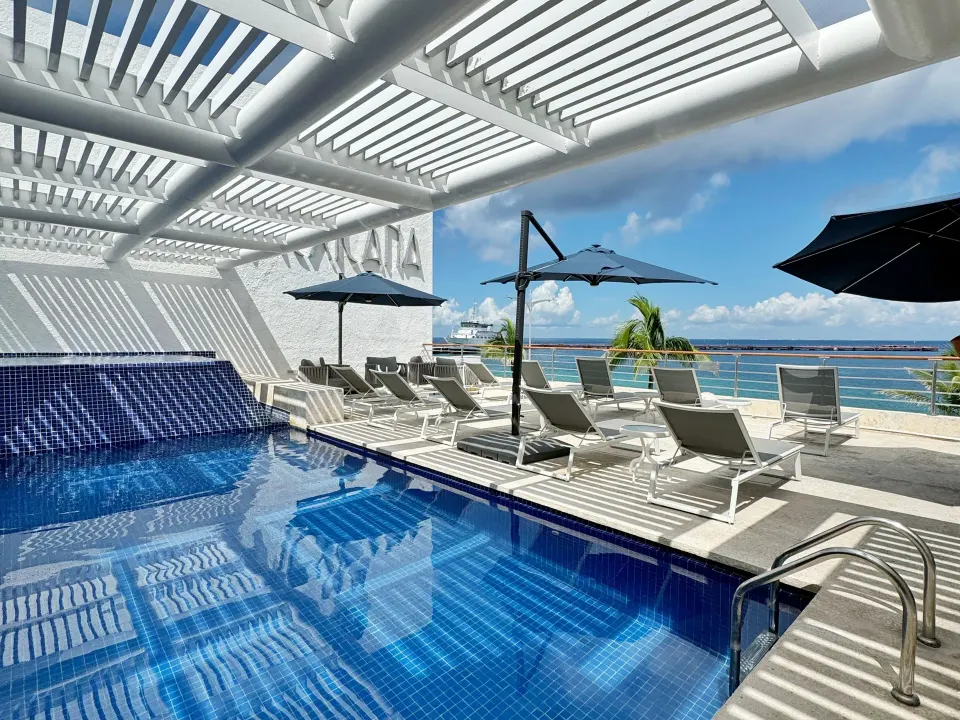 Rooftop pool deck with loungers and ocean view at Casa Mexicana Cozumel