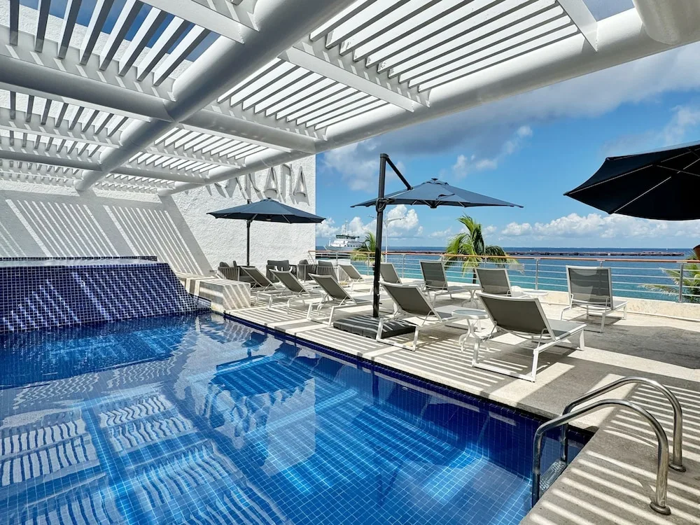 Rooftop pool deck with lounge chairs and ocean view at Casa Mexicana Cozumel
