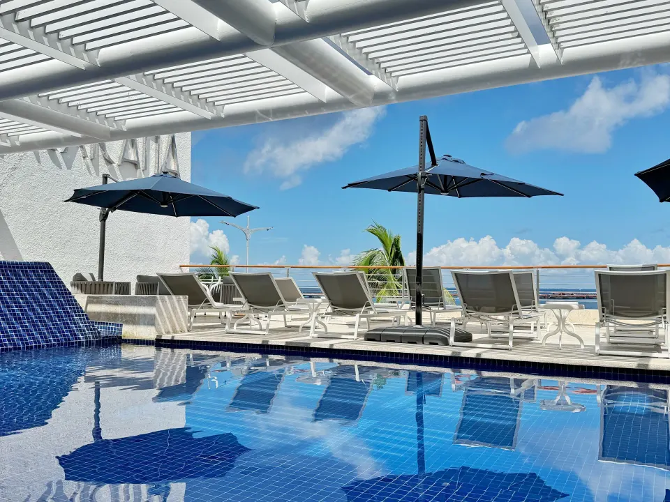 Blue-tiled rooftop pool with lounge chairs and umbrellas at Casa Mexicana Cozumel