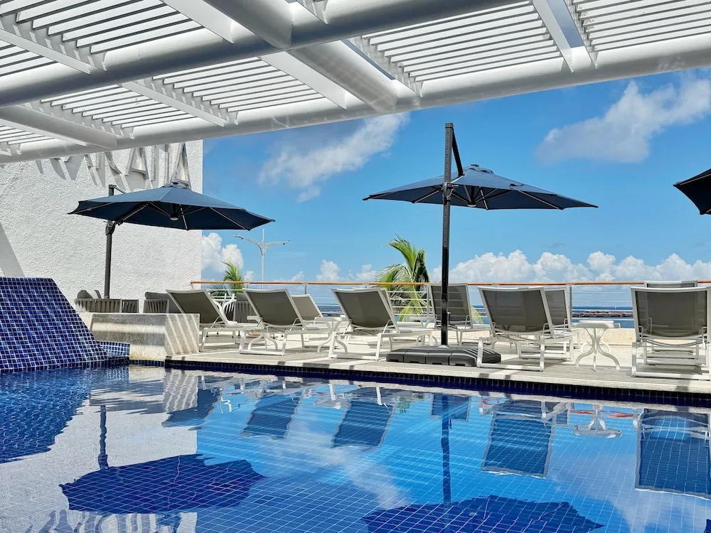 Rooftop pool with lounge chairs and umbrellas at Casa Mexicana Cozumel.