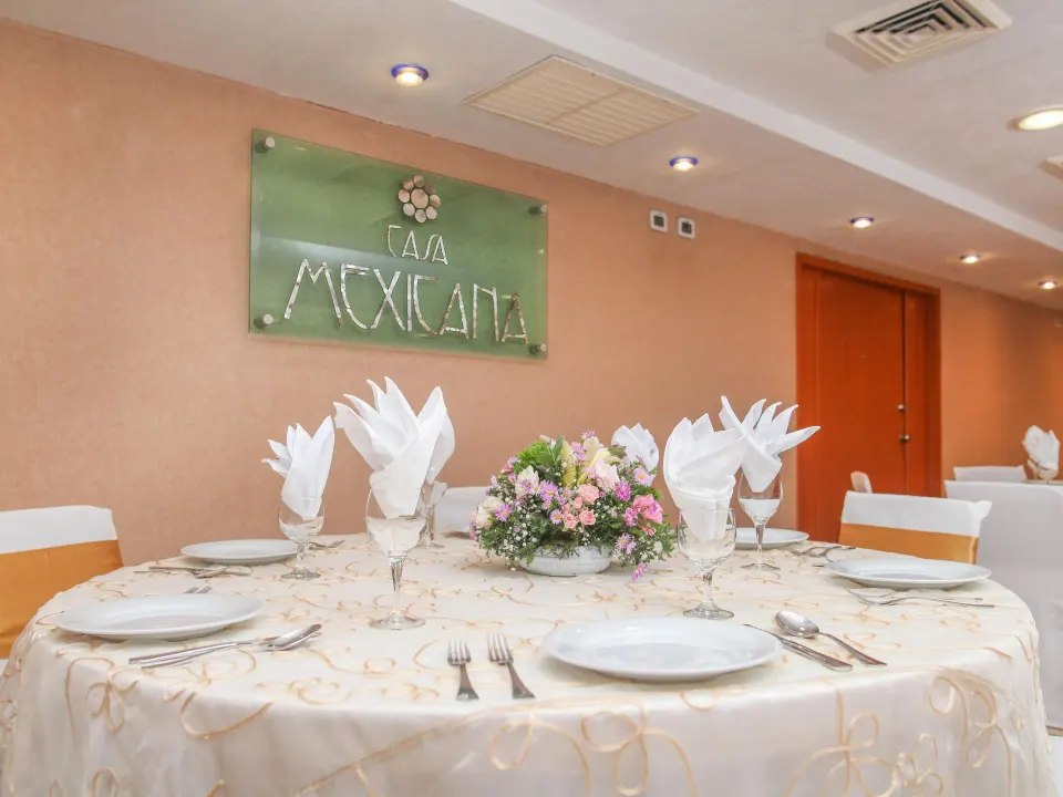 Round dining table set for a meal inside Casa Mexicana Cozumel with floral centerpiece