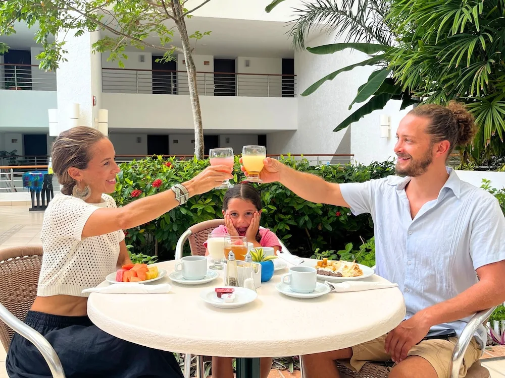Family toasting with juice at a table in the Casa Mexicana Cozumel dining area.