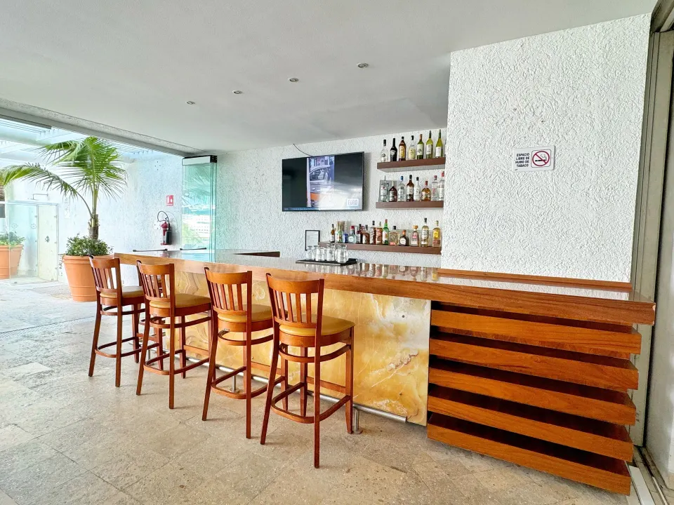 Wood bar counter with stools and shelves of spirits at Casa Mexicana Cozumel