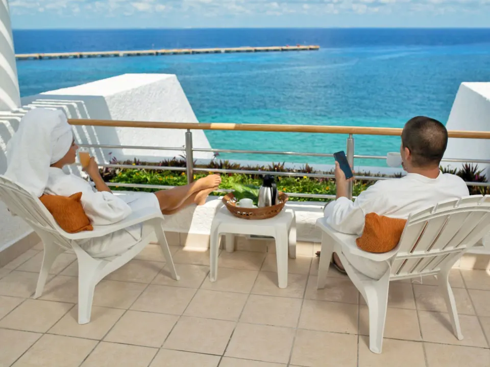 Two guests in robes relaxing on a balcony overlooking the ocean at Casa Mexicana Cozumel