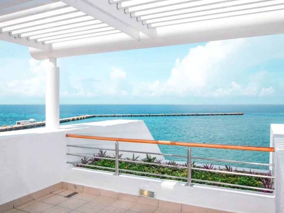 Empty ocean-view balcony with pergola and railing at Casa Mexicana Cozumel