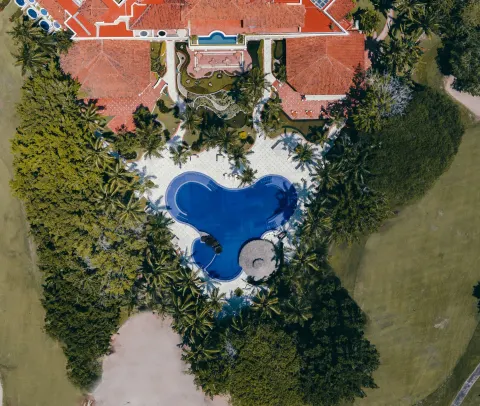 An aerial view shows the curved pool, palms, and red-tile roofs at Casa Velas.