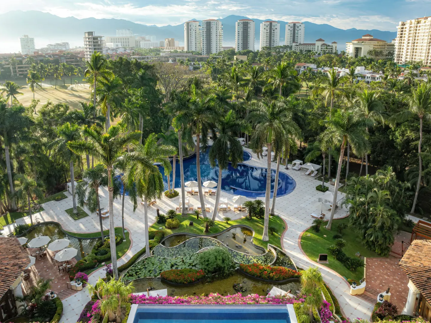 Aerial view of the pool, gardens, palms, and surrounding city at Casa Velas.