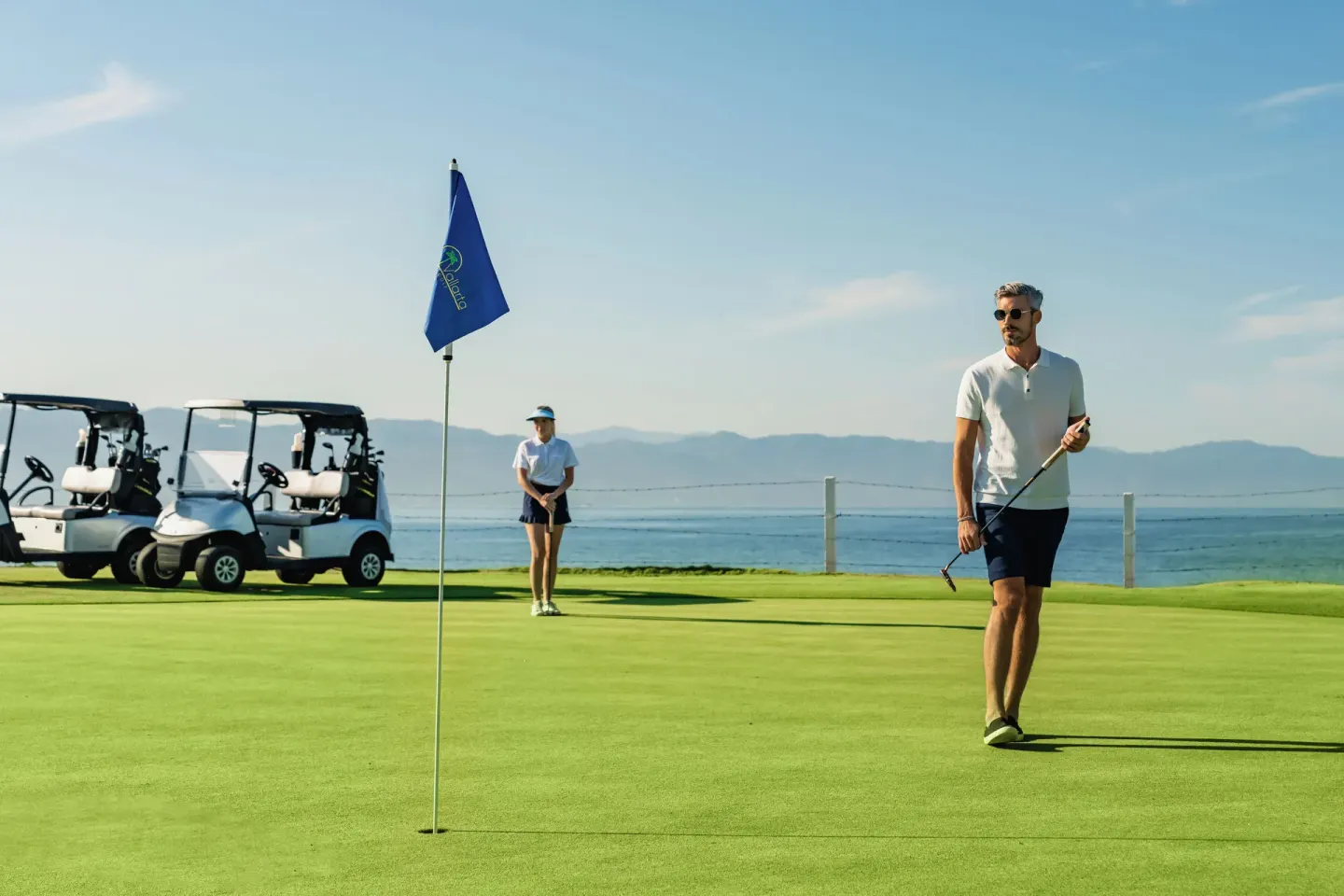 Golfers stand by carts on a coastal green near Casa Velas.