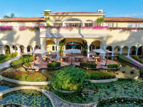 Courtyard with arched terraces, umbrellas, ponds, and flowers at Casa Velas.