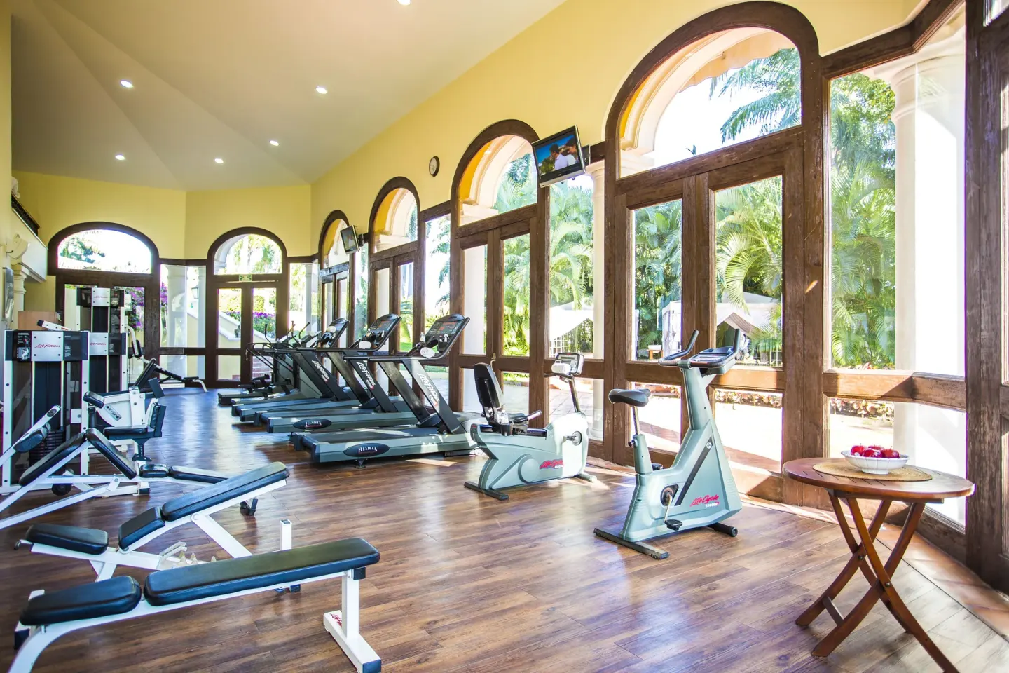 Fitness room with treadmills, exercise bikes, and arched windows at Casa Velas.