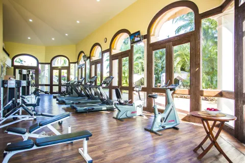 Fitness room with treadmills, exercise bikes, and arched windows at Casa Velas.