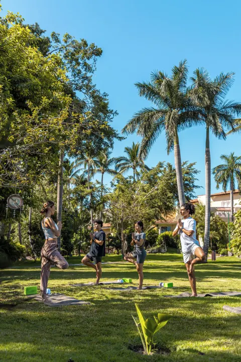 Yoga group balancing on one leg in the gardens at Casa Velas.