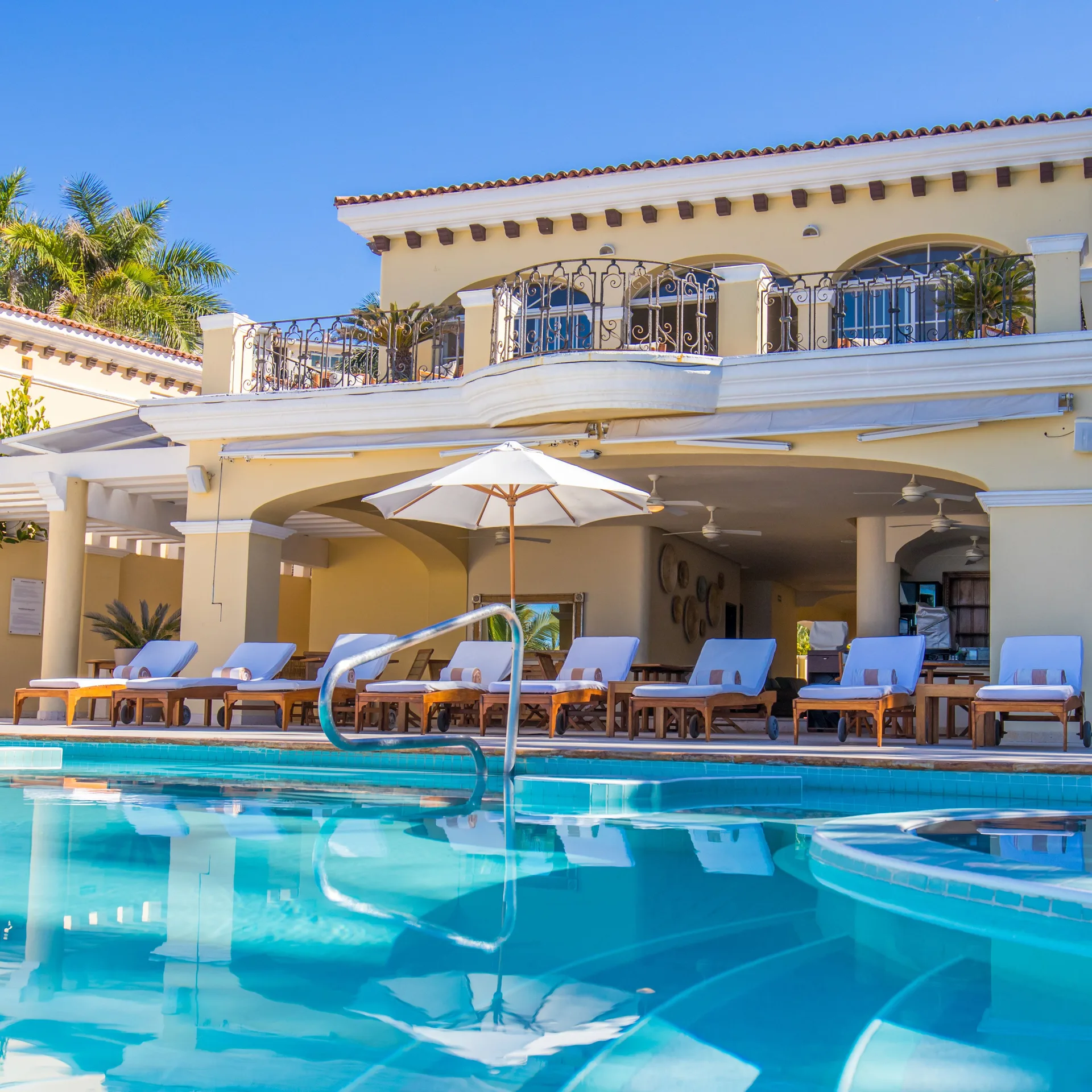 Pool deck with loungers, umbrella, balcony, and swim-up edge at Casa Velas.