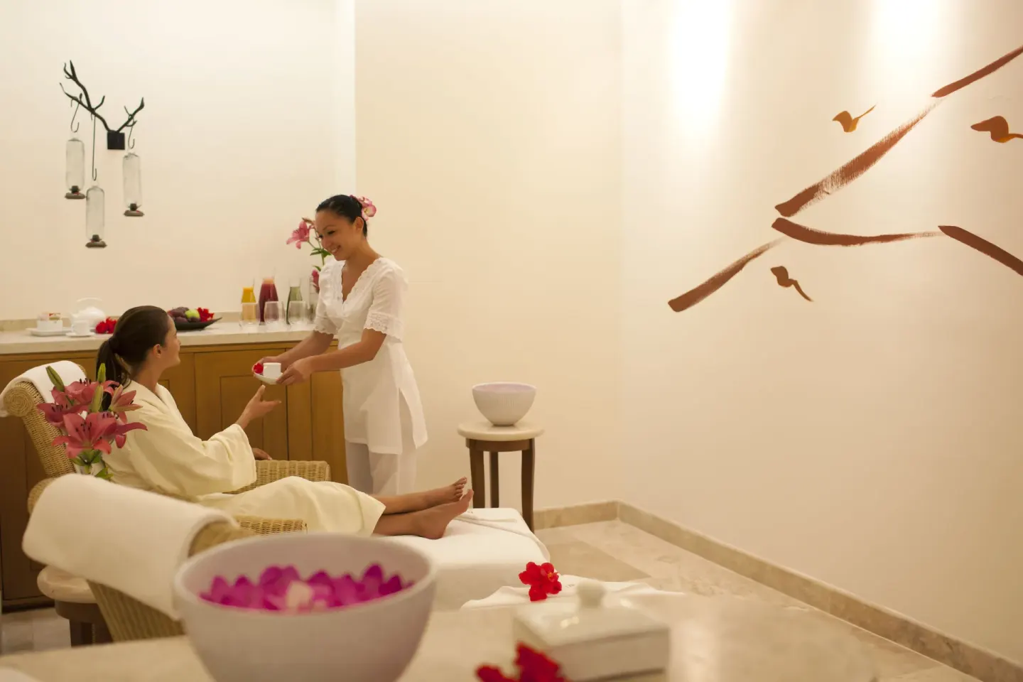 Spa attendant serves a drink to a guest in a treatment lounge at Casa Velas.
