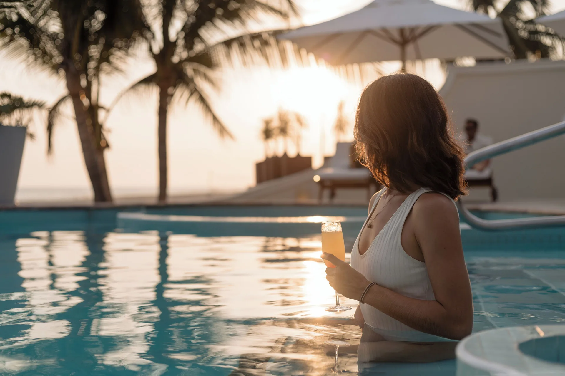 Guest holding a drink in a pool at sunset at Casa Velas.