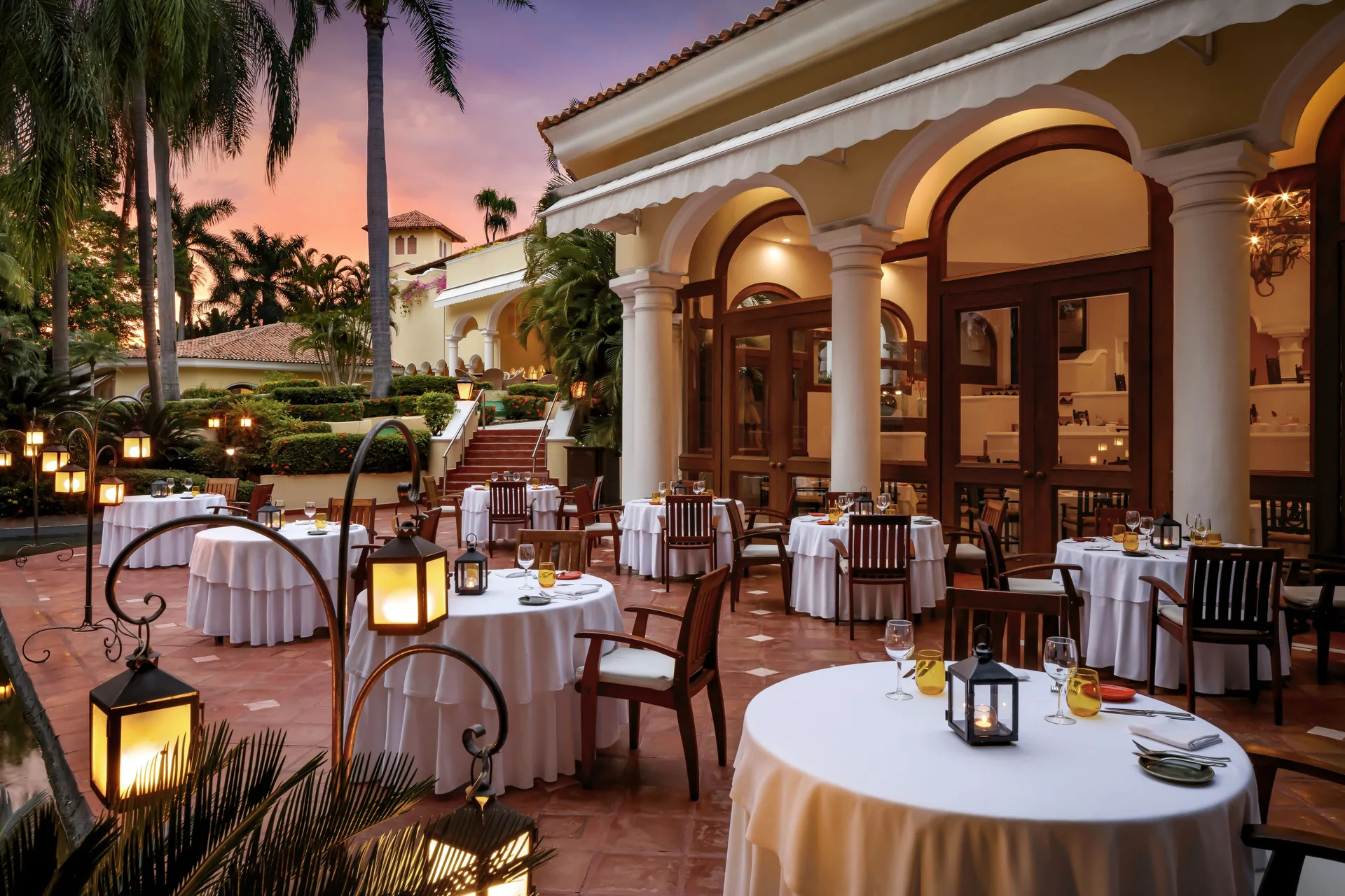 Terrace dining with round white-clothed tables and lanterns at Casa Velas.