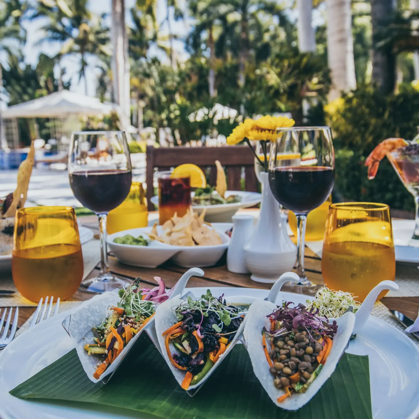 Outdoor table with plated salads, wine, and yellow glassware at Casa Velas.