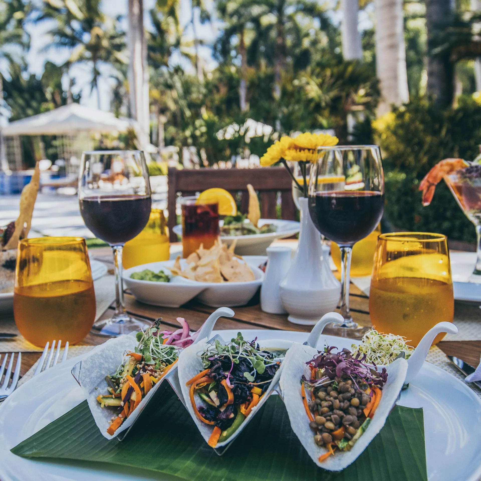 Outdoor table with plated salads, wine, and yellow glassware at Casa Velas.
