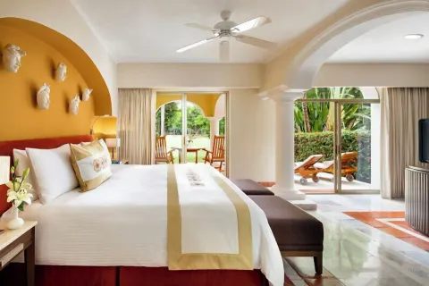 Grand Class Plus king bed with arched columns and terrace access at Casa Velas.