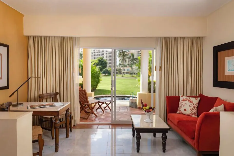 Grand Class Suite sitting area with sofa, desk, terrace, and lawn view at Casa Velas.