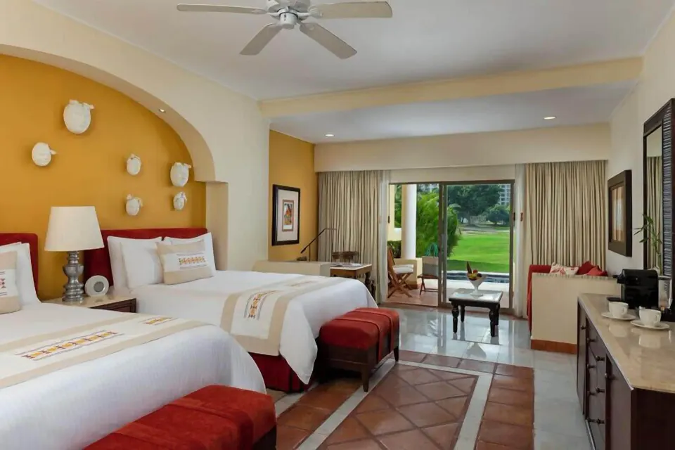 Grand Class Suite with two beds, patio doors, and garden view at Casa Velas.