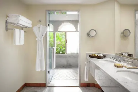 Master Suite bathroom at Casa Velas with marble vanity, robes, towels, and glass shower entrance.