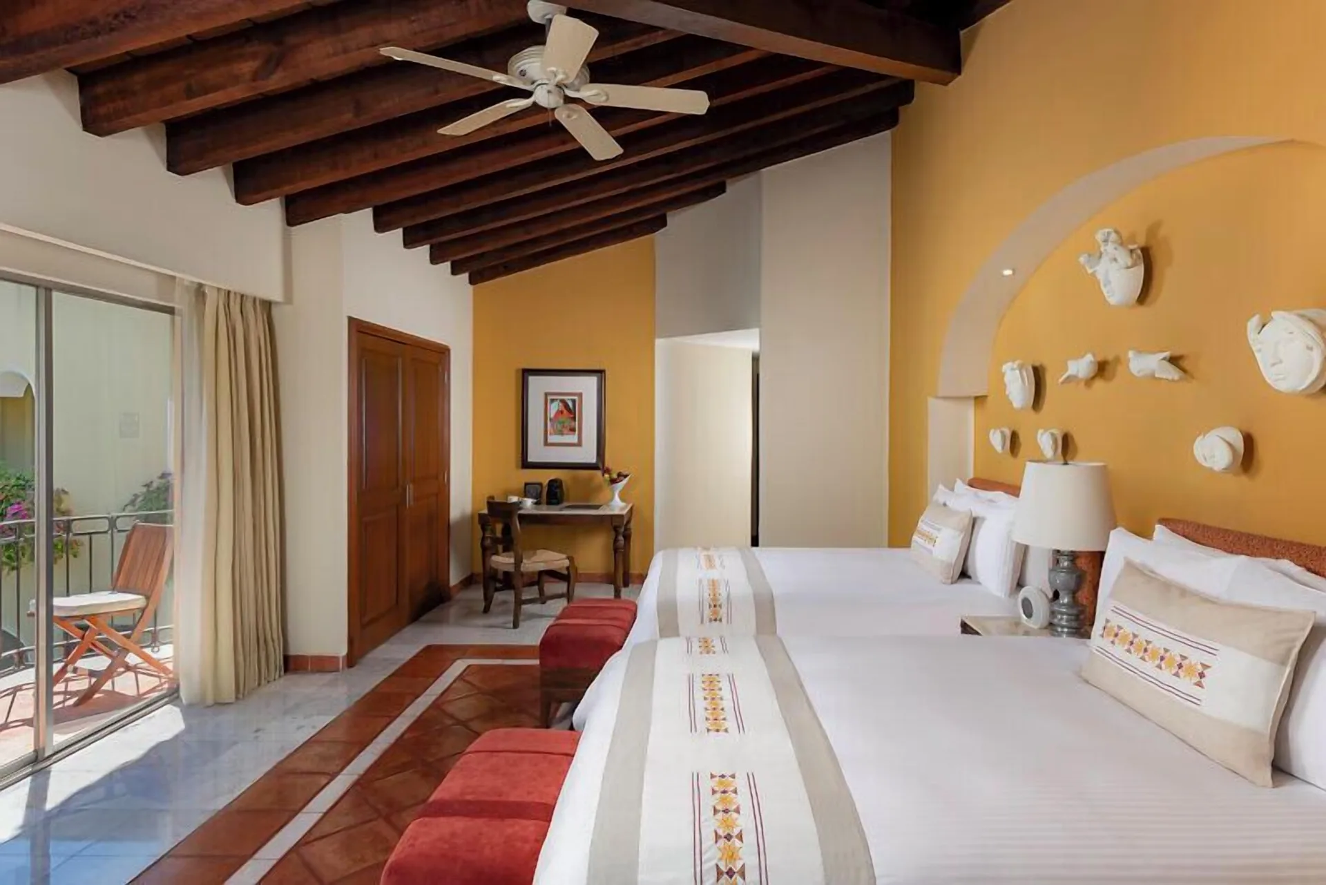 Master Suite bedroom at Casa Velas with two beds, balcony seating, desk, and wood-beam ceiling.