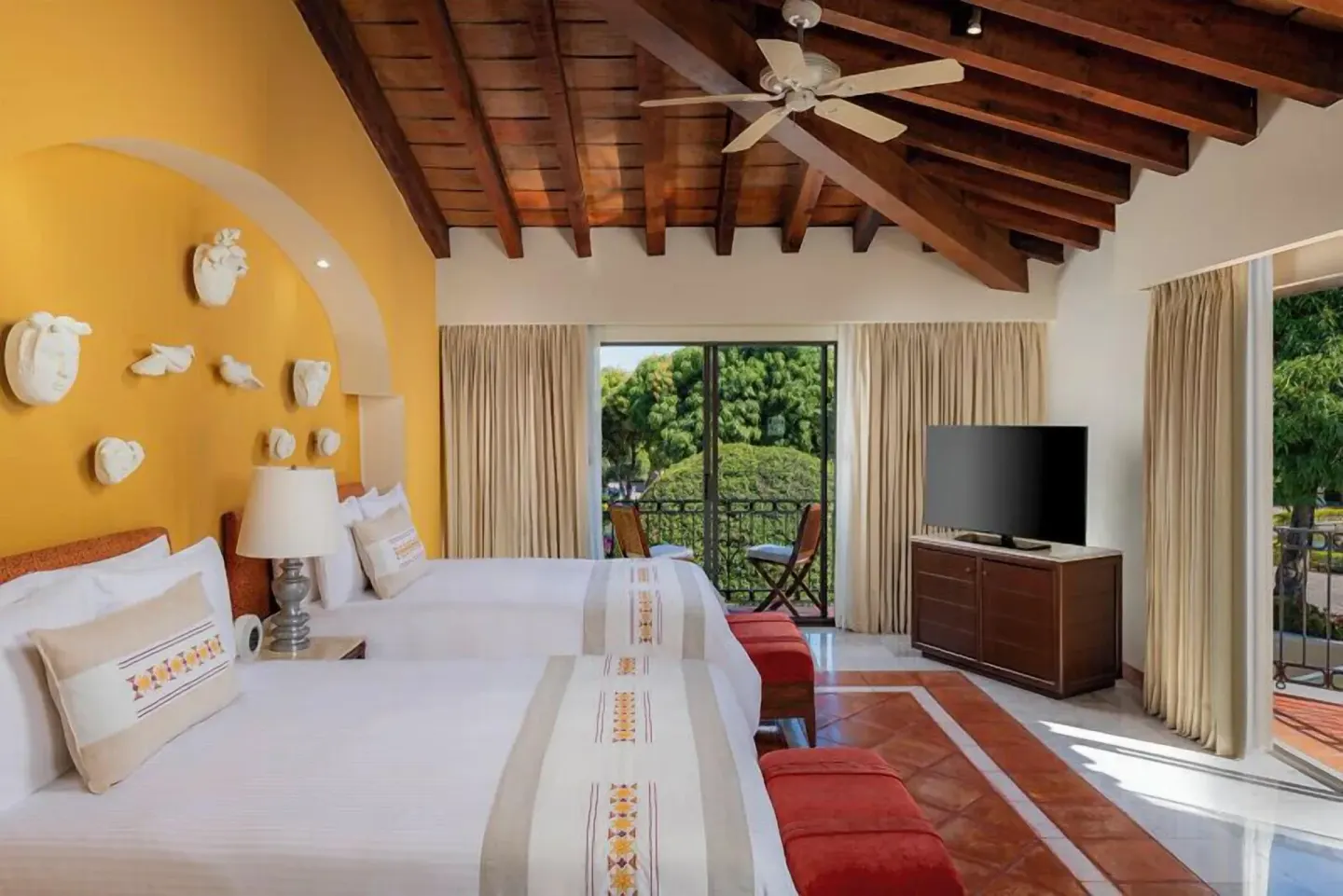 Master Suite at Casa Velas with two beds, vaulted wood ceiling, TV, and garden-facing balconies.