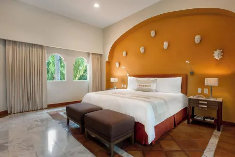 One Bedroom Ambassador Suite king bed with orange arched headwall at Casa Velas.