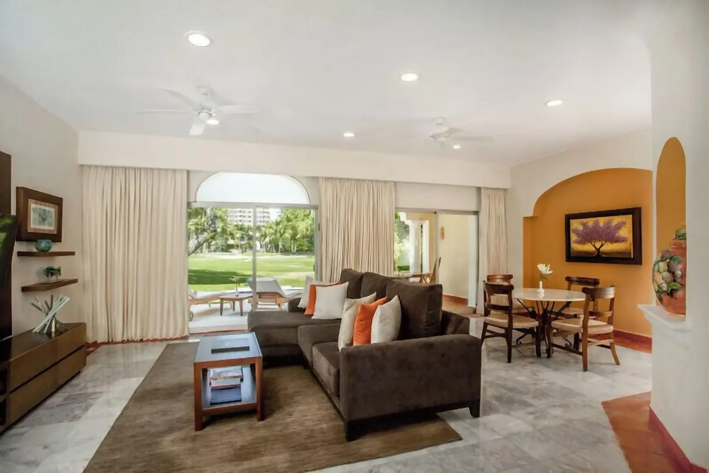 One Bedroom Ambassador Suite living room with sofa, dining table, and terrace doors at Casa Velas.