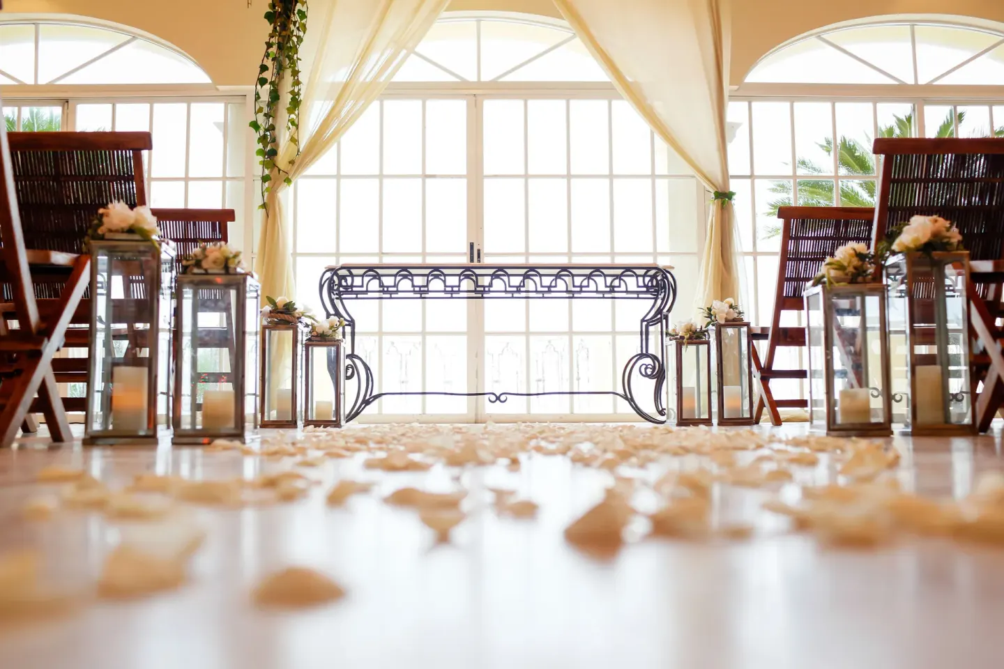 Indoor wedding aisle with petals, lanterns, and tall chairs at Casa Velas.