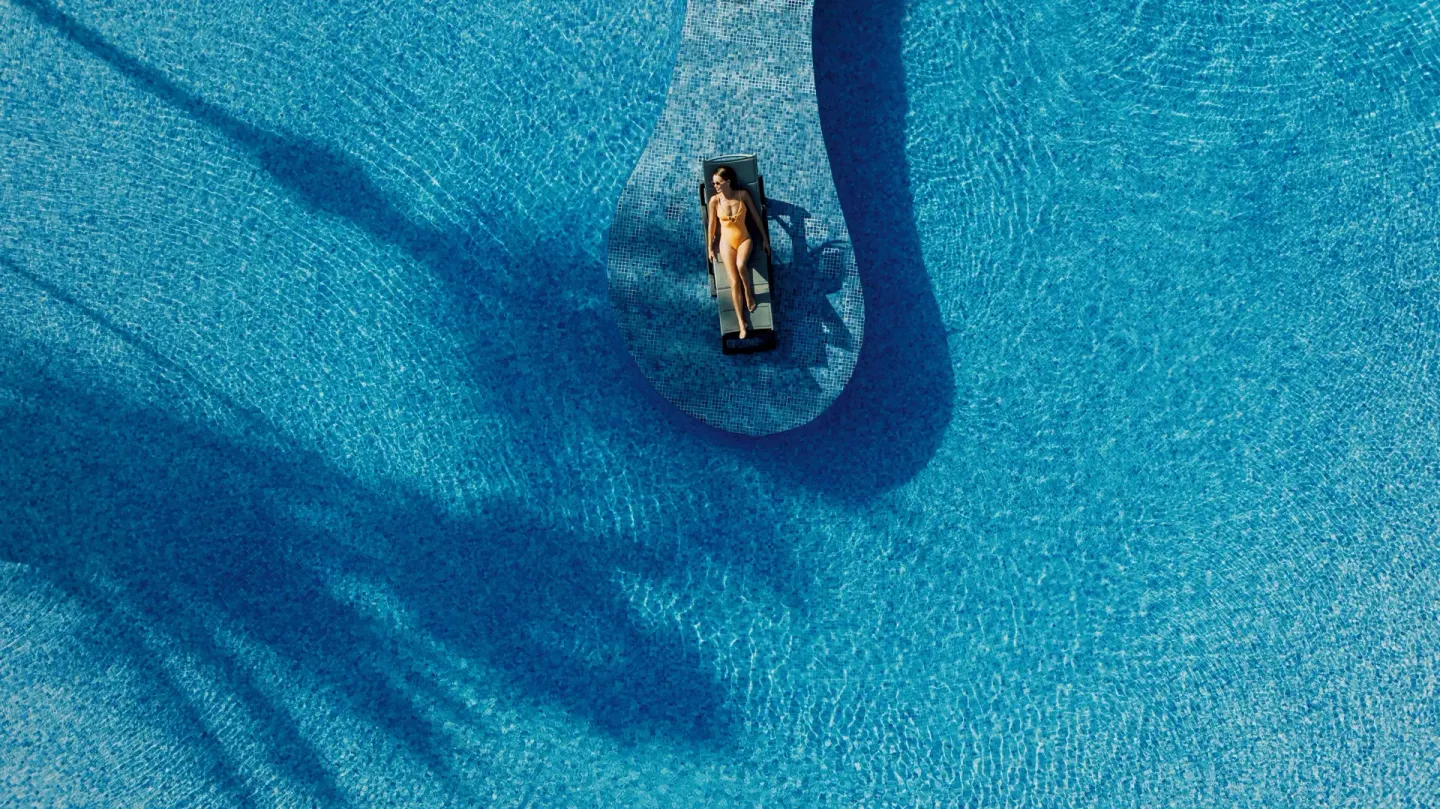 Aerial view of a guest floating on a lounger in the pool at Catalonia Playa Maroma.