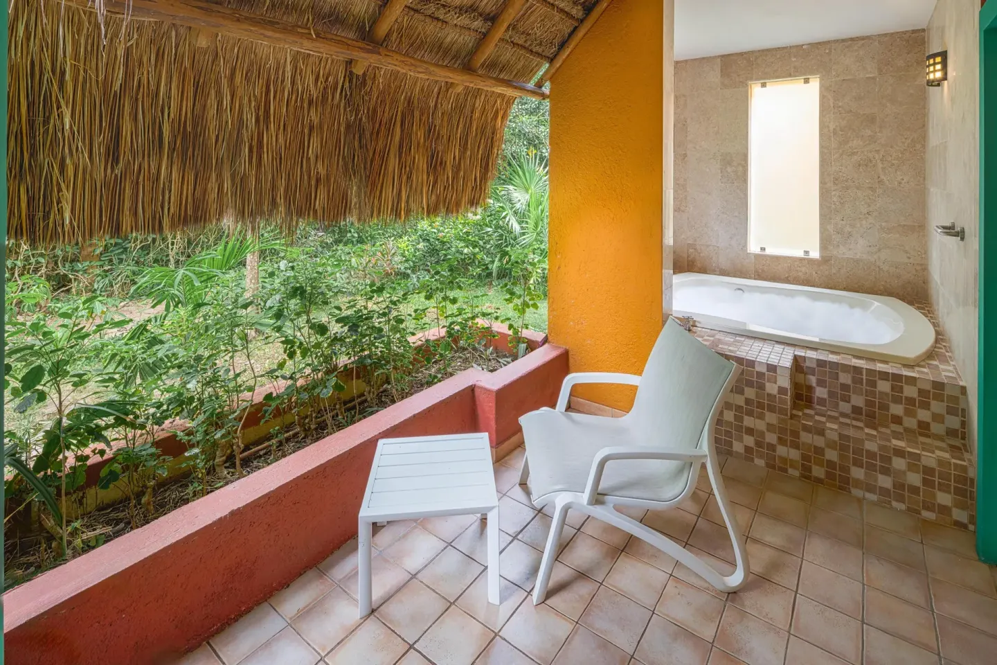 Covered terrace with chair, table and outdoor tub at Catalonia Playa Maroma.